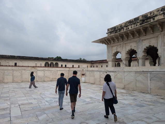      People walking in a white marble courtyard.
  