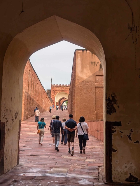       Visitors walking through an arched entrance of an ancient fort.
  