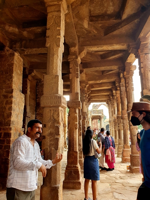       People exploring ancient stone columns and arches.
  