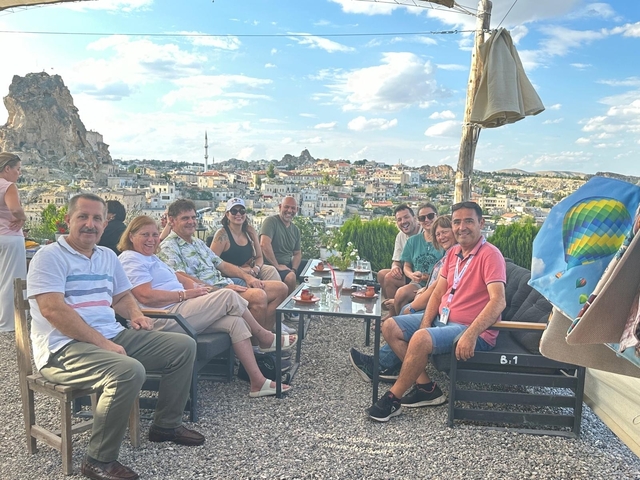 Group of people sitting outdoors with a view of Cappadocia in the background.