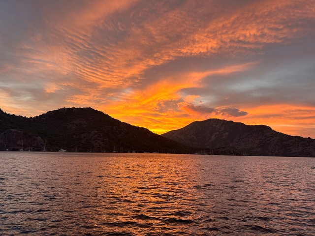 A breathtaking sunset over the sea with a silhouette of mountains.