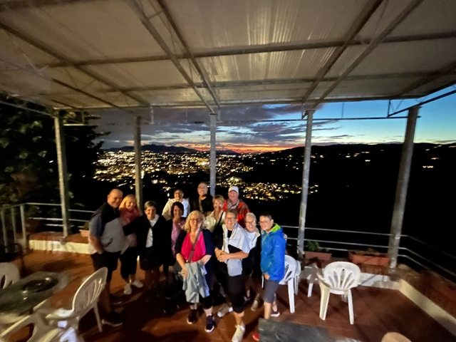      Group photo during sunset on a terrace with city view.
  