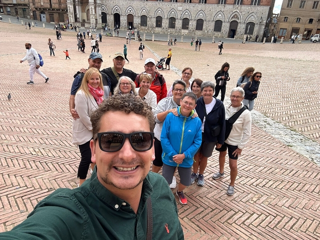 Smiling group gathered in a square with brick patterns.