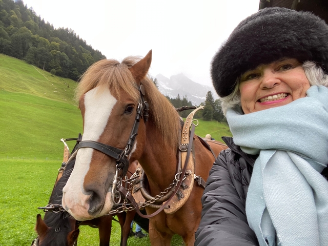       Woman with a horse in lush green surroundings.
  