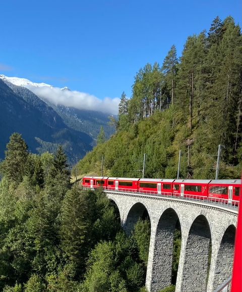       Red train on a scenic mountain route.
  