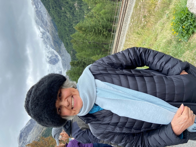       Woman in winter clothing with snowy mountain in the background.
  