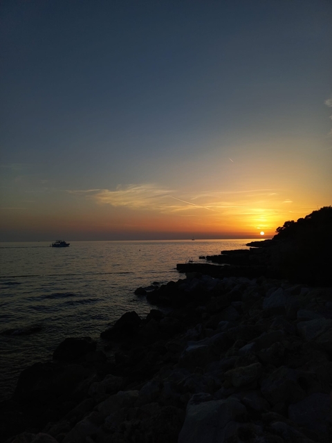 Sunset over the sea with a boat.