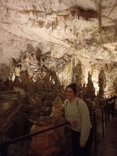 A woman in a cave with stalagmites.