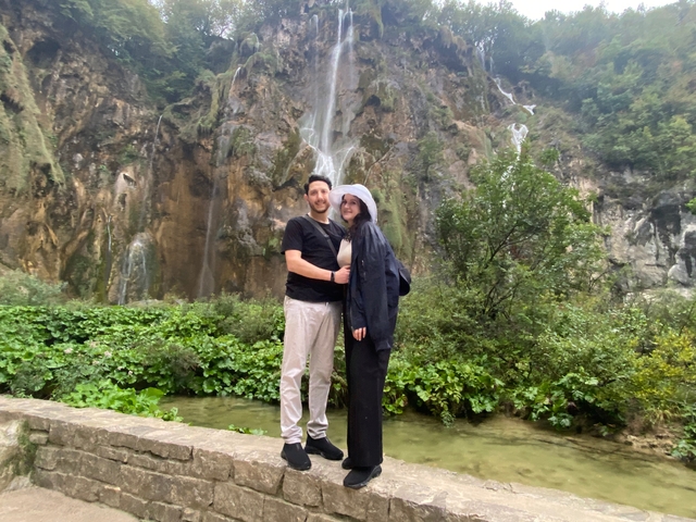A couple posing in front of a waterfall.