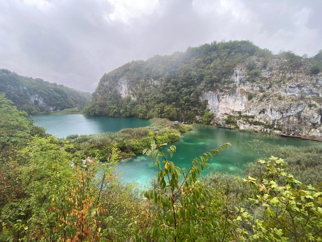 A view of a lake surrounded by lush greenery and cliffs.