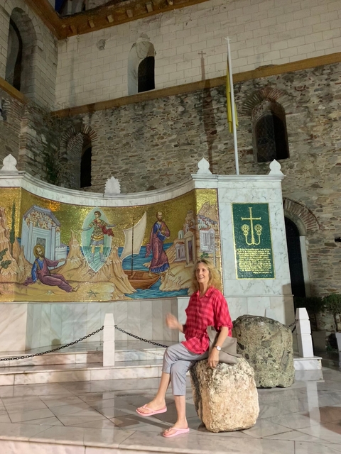 Person standing in front of a decorative mosaic on a historic wall.