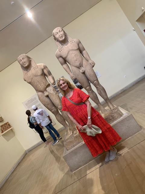       Person posing with ancient statues in a museum.
  
