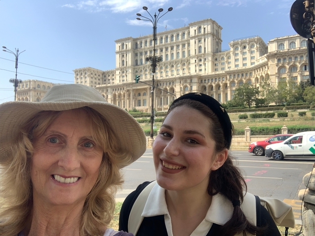 Two people taking a selfie in front of a large government building.