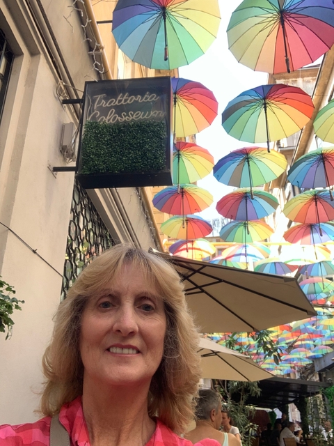 Colorful umbrellas hanging above a street with a person below.