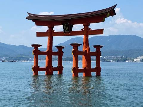 Large orange torii gate standing in the water.