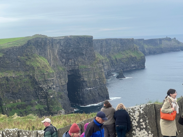 People observing the Cliffs of Moher with the sea in the background.