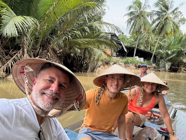 Group of people in traditional hats on a boat in a river.