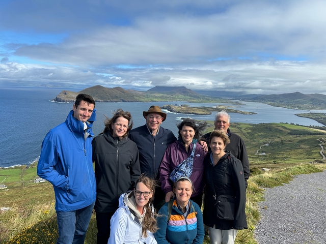       Group of people with a scenic hilly landscape and sea view.
  
