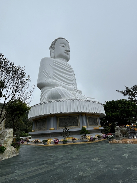       Large white Buddha statue in an outdoor setting.
  