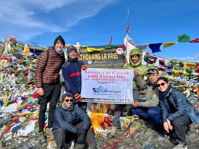 Group of hikers posing with signs at Thorong La Pass.