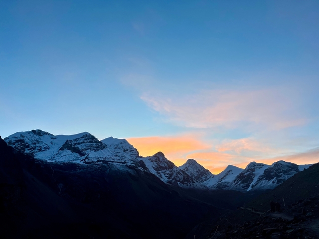 Snow-capped mountain peaks at sunset with a clear sky.