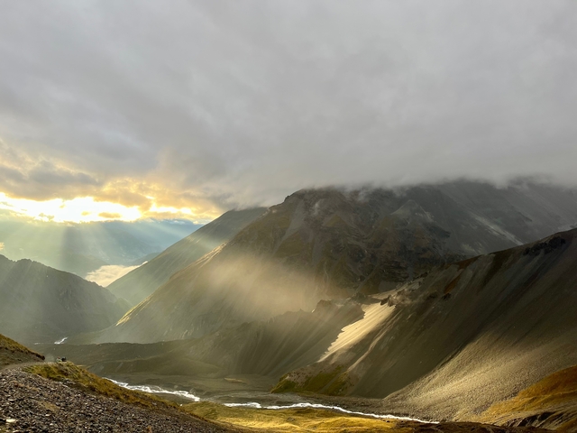 Scenic view of a mountainous landscape with sunlight shining through clouds.