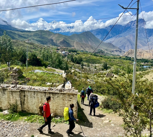 Group of people hiking on a path with mountains in the background.