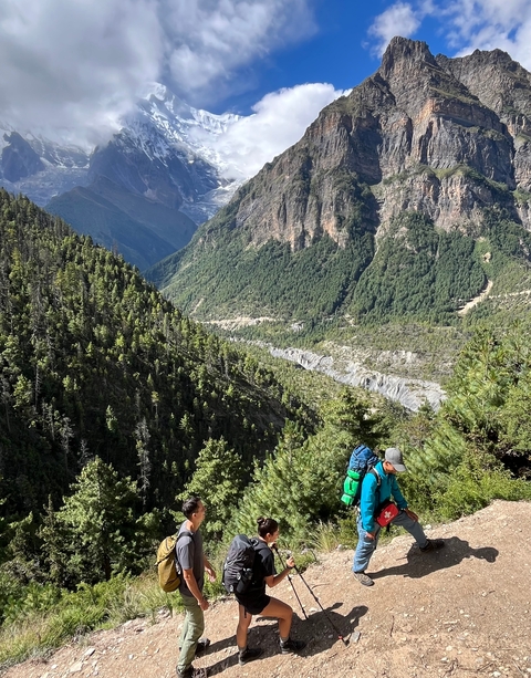 Person with a backpack hiking along a lush green valley.
