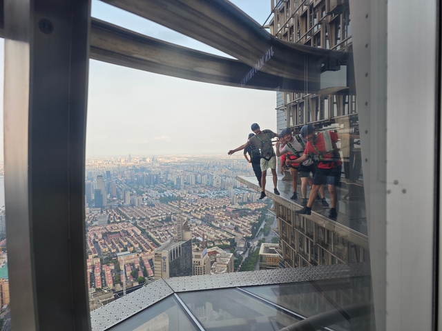 People in a glass walkway high above a city.