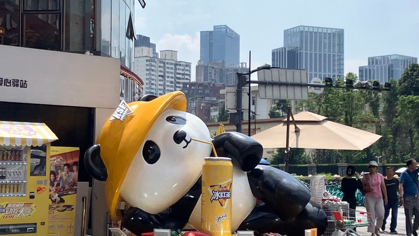       A panda mascot advertising a drink in an urban area.
  