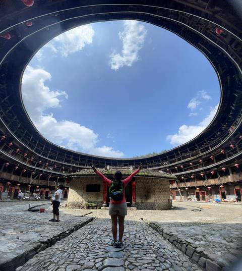 Person inside a circular structure raising arms to the sky.