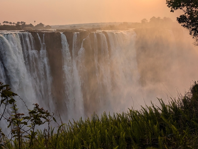 Waterfall cascading over a wide cliff with mist rising.