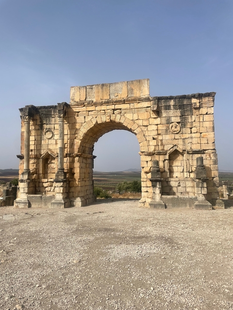 An ancient Roman arch standing in a barren landscape.