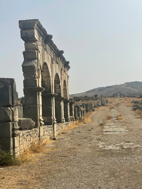 Part of an ancient stone structure beside a long pathway.