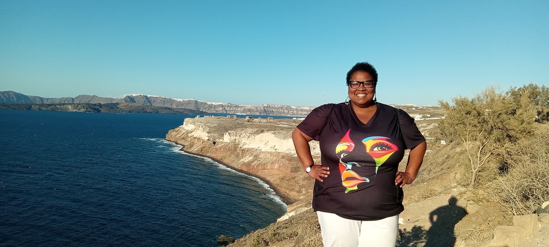 A person standing on a cliff with a scenic ocean view.