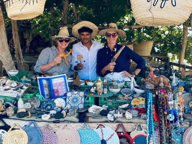 Three people behind a table of colorful souvenirs and trinkets.