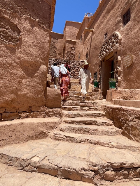       People walking up stone steps in a narrow alley of an old town.
  