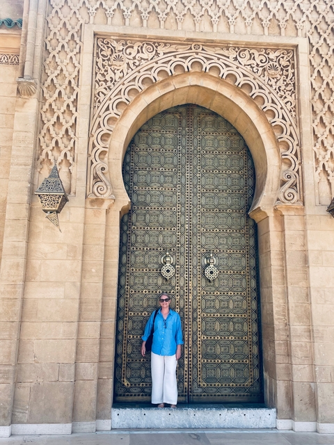       Person posing in front of an intricately carved large door.
  
