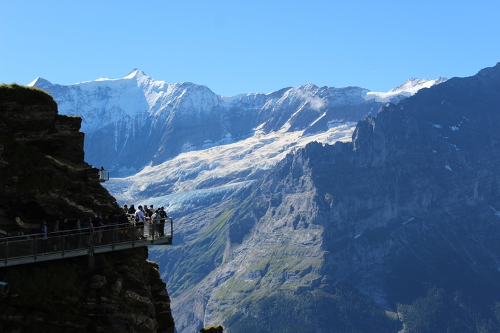 Tourists on a viewing platform with a mountain backdrop.