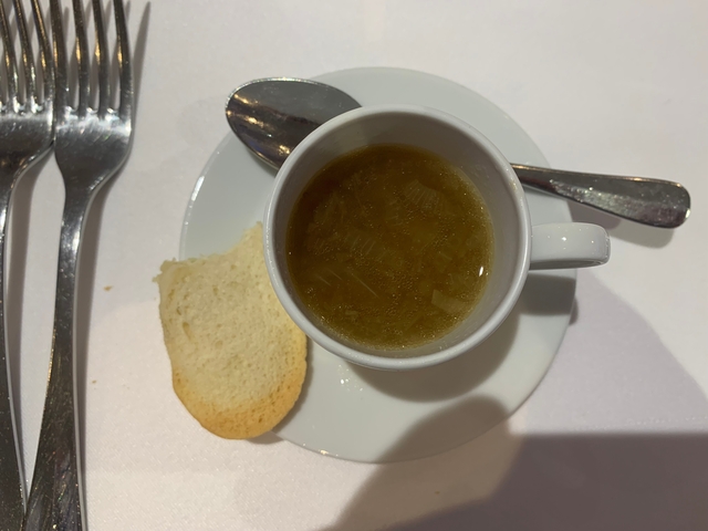 Cup of soup with a bread slice and cutlery.