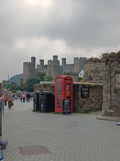 Castle with people and a red phone booth in front.