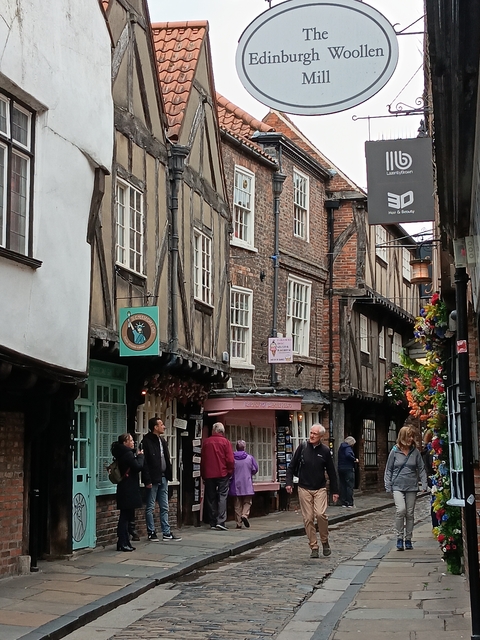 People walking through a narrow cobblestone street.