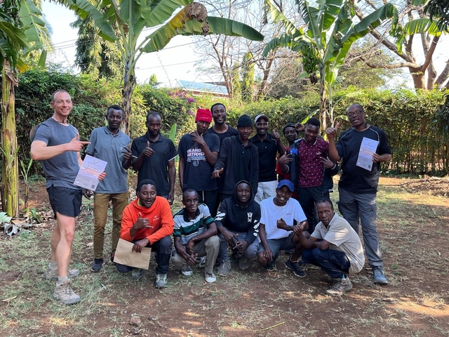       A group of people posing outdoors, some holding certificates.
  