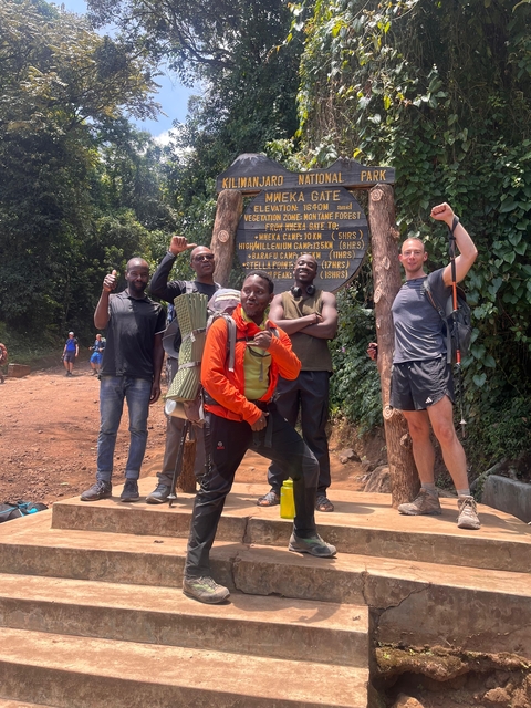       A group of hikers posing at a trekking sign in the forest.
  