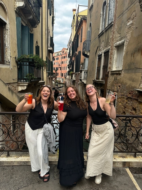 Three women with a canal and colorful buildings.