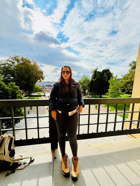 Woman posing in front of a scenic overlook with city view.