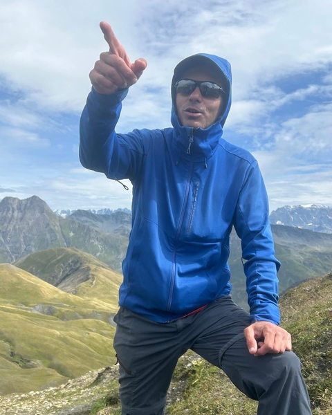       Person in blue facing away with mountain view.
  