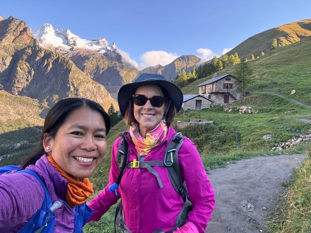       Two hikers smiling with mountain views.
  