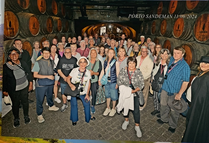 Large group of people posing inside a wine cellar.