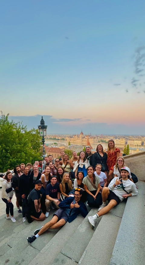 Group with a view of the Budapest Parliament at sunset.